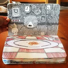 an open book with a drawing of a bear on the front and back cover sitting on top of a wooden table