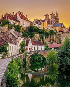 a river running through a small town next to a bridge with buildings on the side