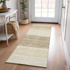 a white door way with a rug on the floor and potted plant next to it