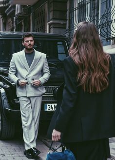 a man in a suit and tie walking down the street with a woman holding a handbag