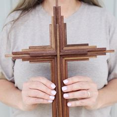 a woman holding a wooden cross with her hands on the cross, while wearing a ring