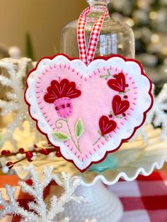 a heart shaped ornament hanging from a christmas tree with red and white decorations