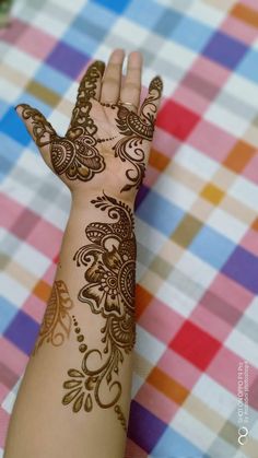 a woman's hand with henna tattoos on it and checkered tablecloth