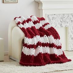 a red and white crocheted afghan sitting on top of a couch next to a fireplace