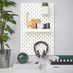 a white shelf with headphones, books and a potted plant