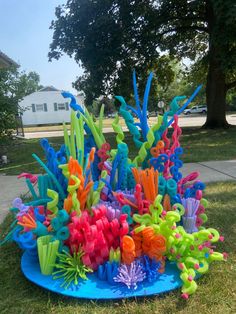 a sculpture made out of plastic letters and seaweed on the grass in front of a house