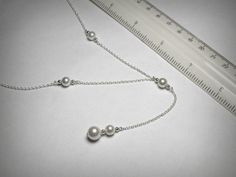 "A classic \"Y\" necklace, or lariat necklace, with faux Swarovski pearls, finished in solid sterling silver. 16 inches in length with the drop measuring an additional 3.25 inches. Or if you like, specify an exact length(s). Also available in 14K yellow gold filled. Ships in 2 to 3 business days." Sterling Silver Lariat Necklace With Pearl Drop, Sterling Silver Pearl Drop Lariat Necklace, Sterling Silver Lariat Necklace With Pearl Pendant, Sterling Silver Pearl Drop Lariat Necklace As Gift, Silver Lariat Pearl Necklace With Adjustable Chain, Sterling Silver Lariat Necklace With Pearl Drop As Gift, Sterling Silver Lariat Pearl Necklace With Adjustable Chain, Silver Backdrop Necklace With Pearl Chain For Gift, Formal White Sterling Silver Lariat Necklace