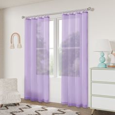 a living room with purple curtains and a white chair