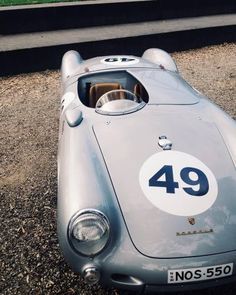 an old race car is parked on the gravel