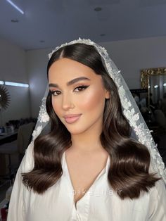 a woman with long hair wearing a wedding veil and white dress is looking at the camera