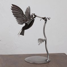 a metal bird sculpture on top of a wooden table