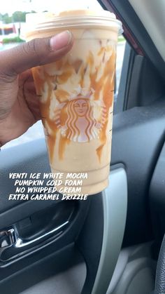 a person holding up a starbucks cup in their car door window with the words, ventti ice, white mocha and whipped cream on it