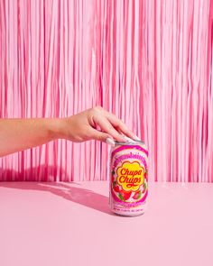 a woman's hand reaching for a can of cupcakes on a pink table