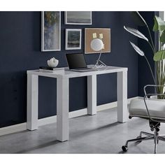 a desk with a laptop on it in front of a blue wall and white chair