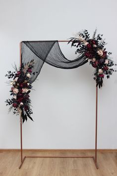 an iron frame decorated with flowers and foliage for a wedding ceremony or special occasion, on a wooden floor