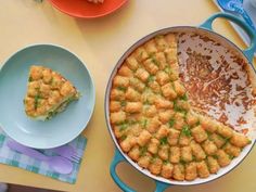 a pan filled with food sitting on top of a table next to plates and utensils