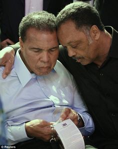 two men sitting next to each other while looking at something on a piece of paper