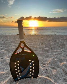 a paddle sitting on top of a sandy beach next to the ocean under a sunset