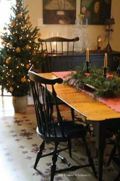 a dining room table with two chairs and a christmas tree