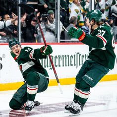 two hockey players on the ice with their arms in the air