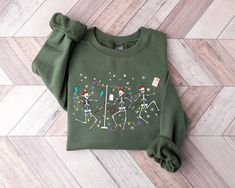 a green sweater with skeletons and christmas lights on it, sitting on a wood floor