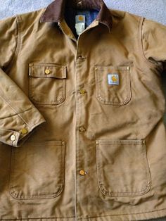 CARHARTT workwear chore coat Classic heavy cotton duck tan fabric Brown corduroy collar Caramel tan distressed cotton canvas duck fabric Blanket lining Logo metal riveted buttons Loaded with pockets 100% cotton outer Moderately distressed with work and wear Labeled Men's size 42 Regular Approx Large Back neck to hem: 30" Armpit to armpit: 25" Sleeve: 25" Iconic Carhartt workwear Distressed /worn vintage condition Heavy fabric has soften with medium wear Stored in my smoke free, pet free home Please read shop and shipping policies Fabric Blanket, German Men, Tactical Wear, Coat Classic, Duck Fabric, Tan Fabric, Work Coat, Heavy Work, Carhartt Workwear