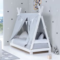 a child's teepee tent bed with stars on the wall and white sheets