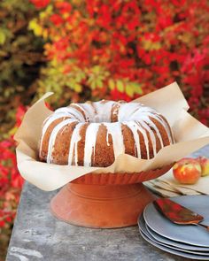 a bundt cake sitting on top of a table next to plates and an apple