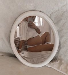 a woman is taking a selfie in the mirror on her bed while laying down