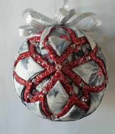 a silver and red ornament hanging on a wall