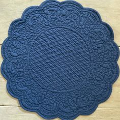 a blue placemat with an intricate design on the front and center, sitting on a wooden