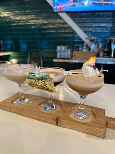 two martinis sitting on top of a wooden tray next to each other in front of a bar