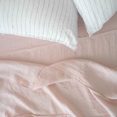 two pillows on top of a bed with pink sheets