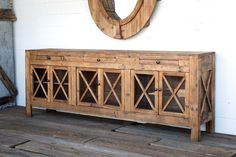 a large wooden cabinet sitting on top of a hard wood floor next to a mirror