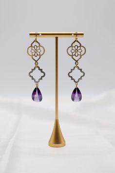 These purple stone earrings feature filigree designs and faceted fancy cut cubic stones, creating a unique and elegant look. The filigree adds intricate detail, while the faceted stones add a touch of sparkle. Perfect for adding a pop of color and sophistication to any outfit. Length: 3.0” Width: 0.86” Closure: Fish Hook Material: Brass with 18K Gold Plating with Rhodium Coating Lead Free and Hypoallergenic Ornate Purple Jewelry With Matching Earrings, Purple Earrings With Intricate Design For Gift, Purple Earrings With Intricate Design As Gift, Ornate Purple Dangle Earrings, Ornate Purple Drop Earrings, Ornate Purple Pierced Earrings, Ornate Purple Dangle Jewelry, Ornate Purple Sterling Silver Earrings, Elegant Purple Earrings For Pierced Ears