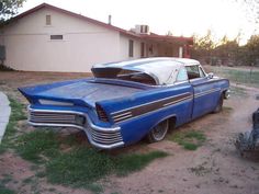 an old blue car parked in front of a house