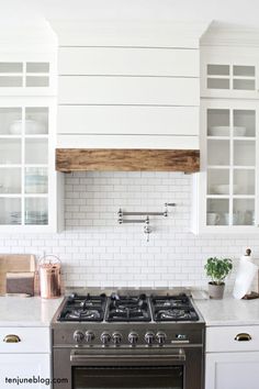 a stove top oven sitting inside of a kitchen next to white cupboards and counter tops