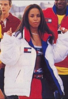 a woman in a red, white and blue jacket is standing next to other people