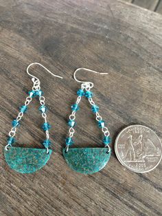 two pieces of jewelry sitting on top of a wooden table next to a dime coin