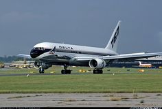 a large jetliner sitting on top of an airport tarmac next to a field