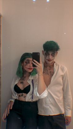 two people dressed up as zombies taking a selfie with a cell phone in front of them