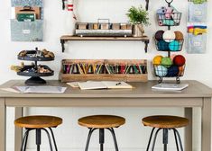 three stools sitting at a table with books and papers on the shelf above it