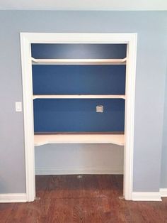 an empty room with blue shelves and wood flooring in the corner, along with hardwood floors