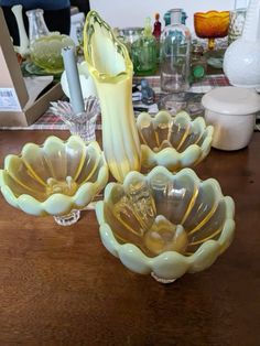 three glass dishes sitting on top of a wooden table next to candles and other items