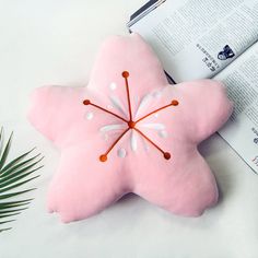 a pink starfish shaped pillow sitting next to an open book