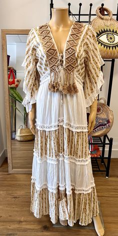 Long kaftan-type dress, made of cotton and with macrame appliqué and fringes. Tassels. Marvelous. Vacation Boho Maxi Dress With Lace Trim, Festival Floor-length Maxi Dress With Tassels, White Ruffled Boho Dress For Beach, White Peasant V-neck Dress, White Boho Ruffled Dress For Beach, Bohemian Lace Trim Dress For Vacation, Flowy Bohemian Dress With Ruffles, Flowy Bohemian Boho Dress With Ruffles, Long Bohemian Dress With Back Tassel Tie-up