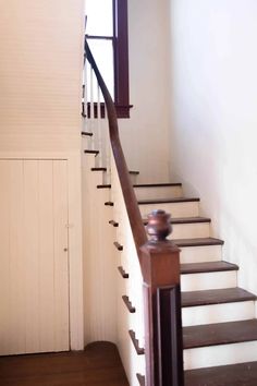 a wooden stair case next to a white wall