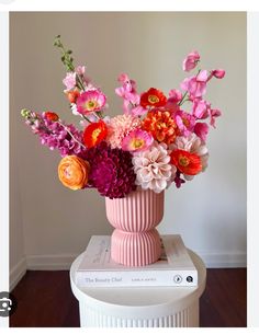 a pink vase filled with lots of colorful flowers