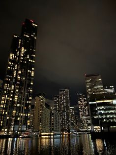 the city is lit up at night with lights reflecting in the water and skyscrapers