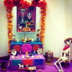 a colorful display with skeletons and skulls on it in front of a mirror, decorated with flowers